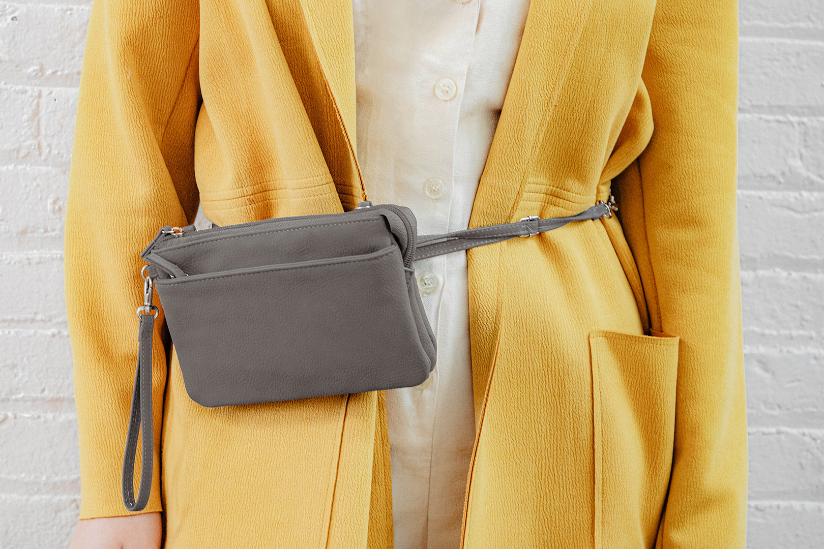 Bags with Built in Wallets - A woman in a yellow jacket with a white top on straps a brady belt bag around her waist.