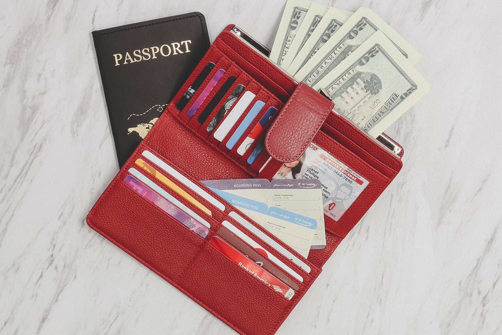 How to Stay Safe While Traveling During The Holidays - Our Red Rio Leather Clutch Lies open on a table full of credit card, money, IDs, and a passport.